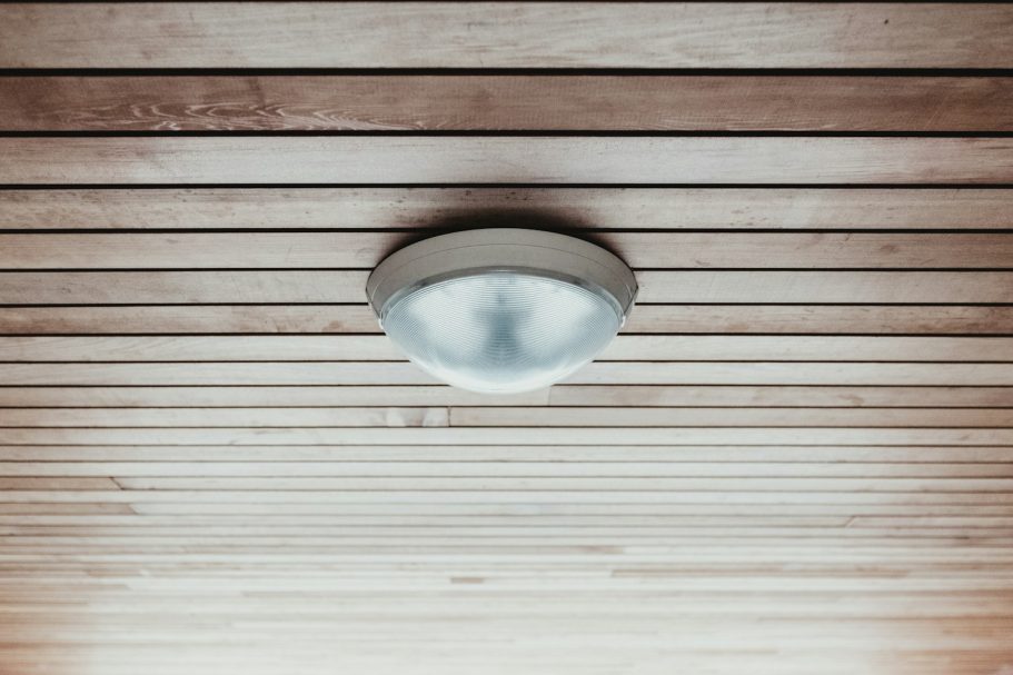 Decke mit Holzpaneelen und einer runden, weißen Deckenleuchte.